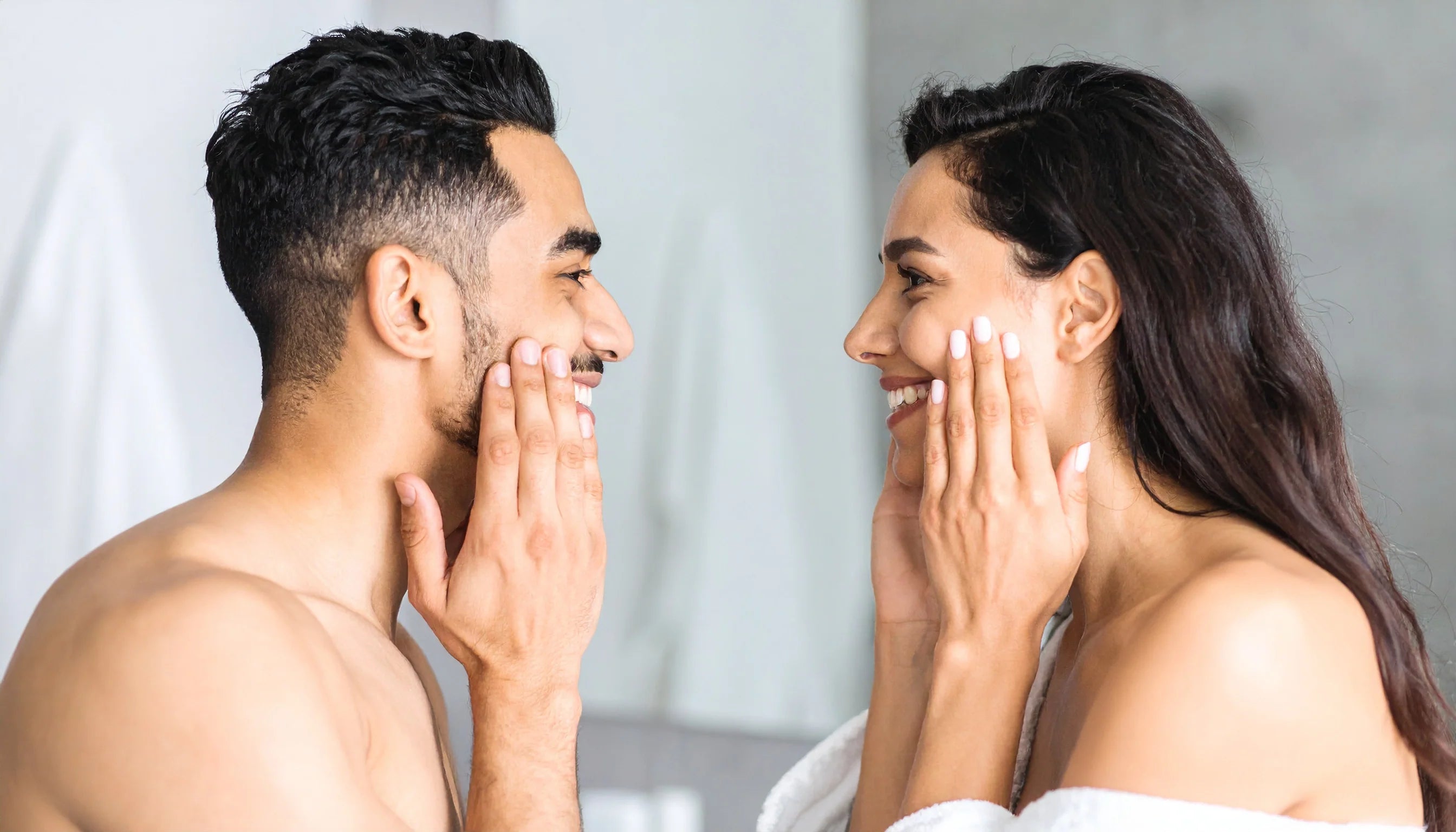 Man and woman applying face cream in a modern bathroom, showing Suvéra’s natural skincare ritual for healthy, radiant skin.