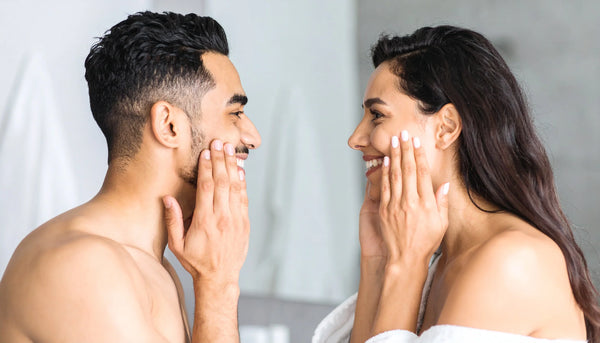 Man and woman applying face cream in a modern bathroom, showing Suvéra’s natural skincare ritual for healthy, radiant skin.