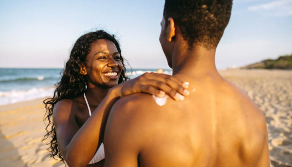 Adult woman applying Suvéra mineral sunscreen SPF30 on man’s shoulder at the beach – vegan sun care, natural skin protection, clean beauty.