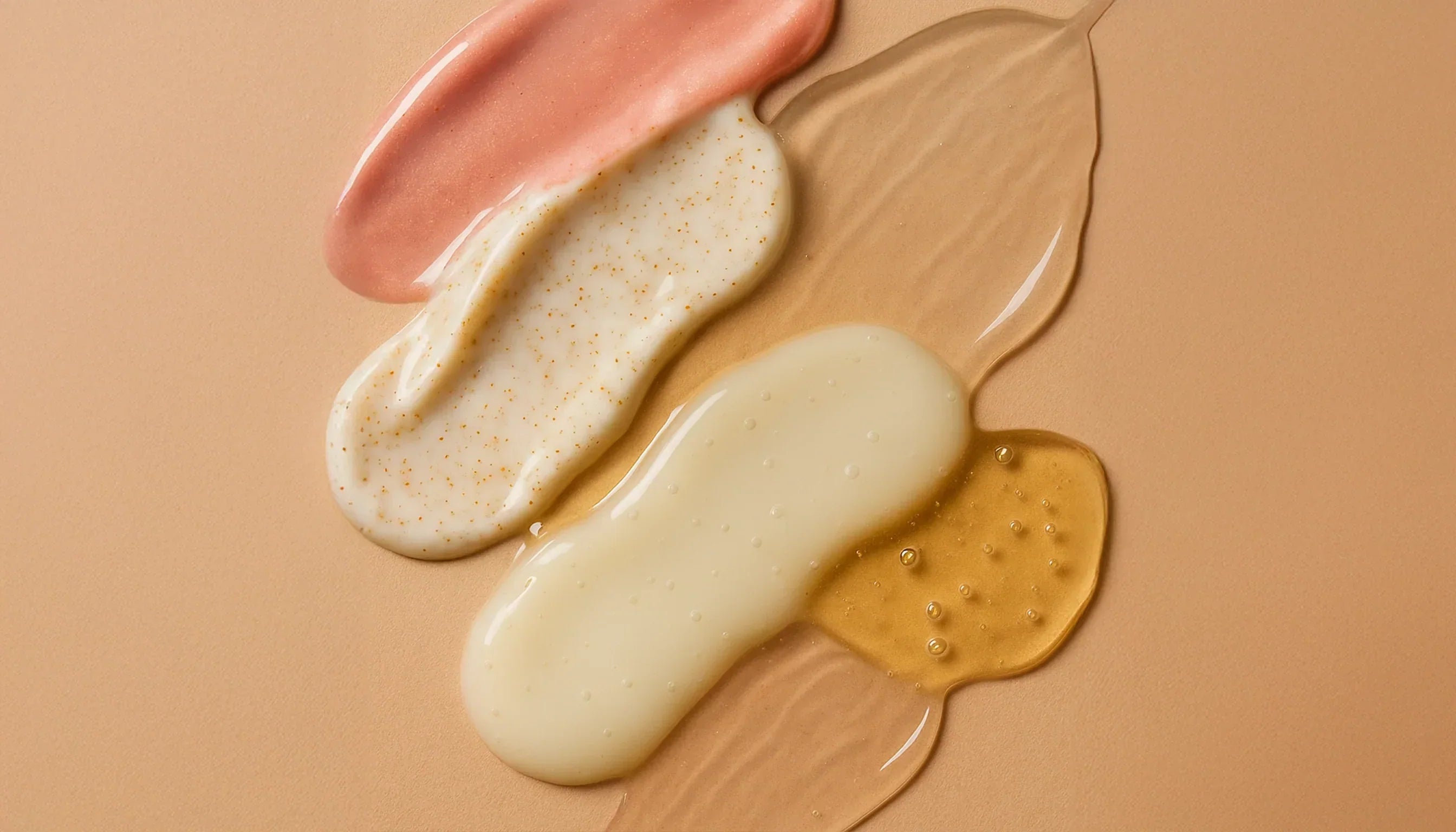 Suvera Beauty Blog — macro close-up of overlapping skincare textures (gel, cream, serum, oil) on a warm beige background