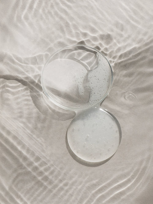 Clear glass with a white powdery substance on a textured beige surface Purifying Toner