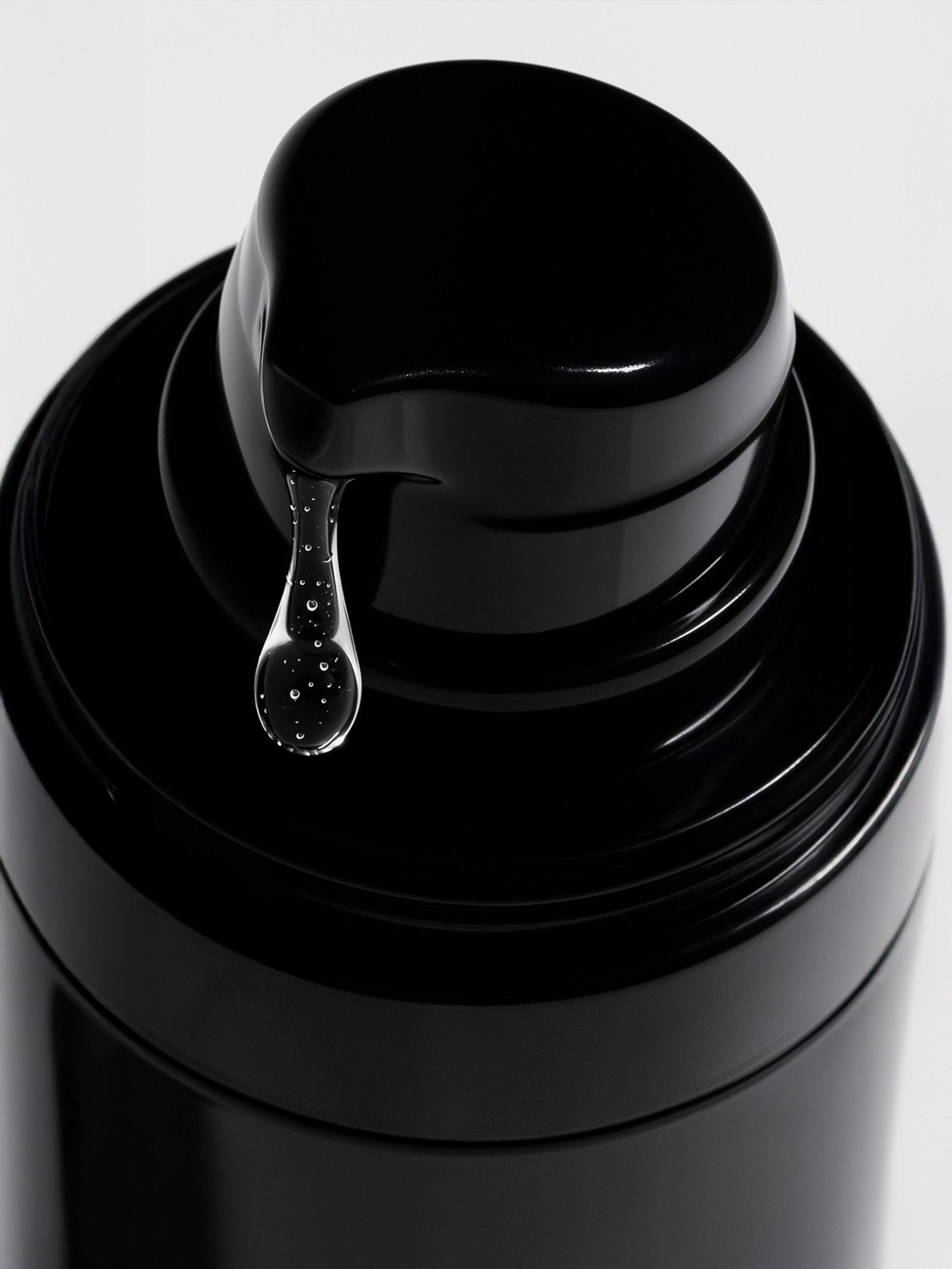 Close-up of a black bottle cap with a droplet of liquid on a white background Oil-Free Hydrating Gel