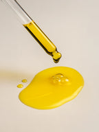 Yellow liquid being dripped from a dropper onto a beige surface Retinol Alternative Natural Oil Serum