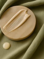 Beige soap bar with a smear of soap on a green fabric background Sensitive Skin Oil-To-Milk Cleanser