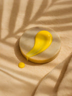 Yellow liquid droplet on a beige stone surface with a soft shadow Vitamin C Serum