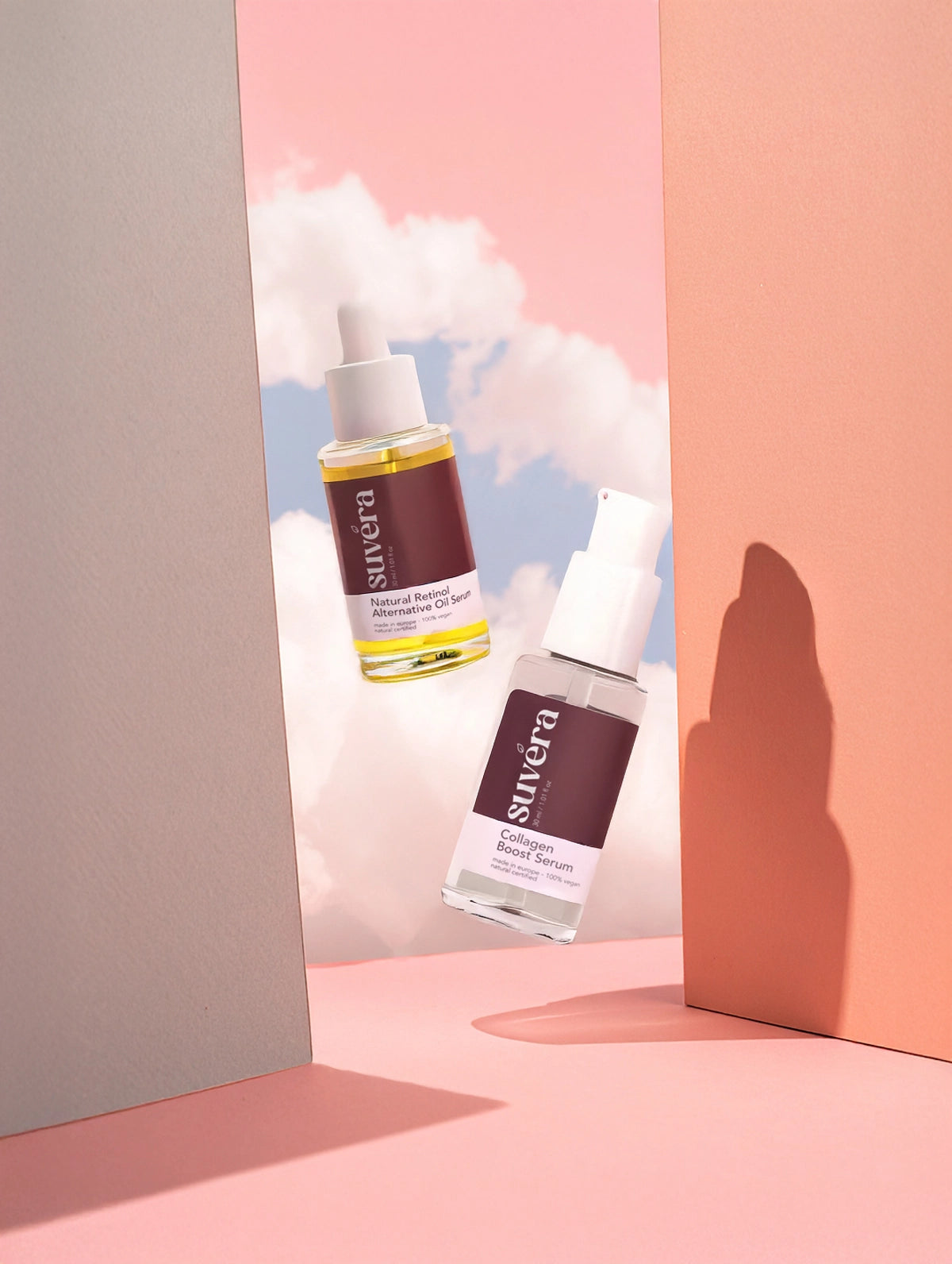 Two skincare serum bottles with visible branding on a pastel pink and beige background Texture close-up of The Weightless Duo: silky oil and water-light serum showing smooth, firm, bright-skin results.