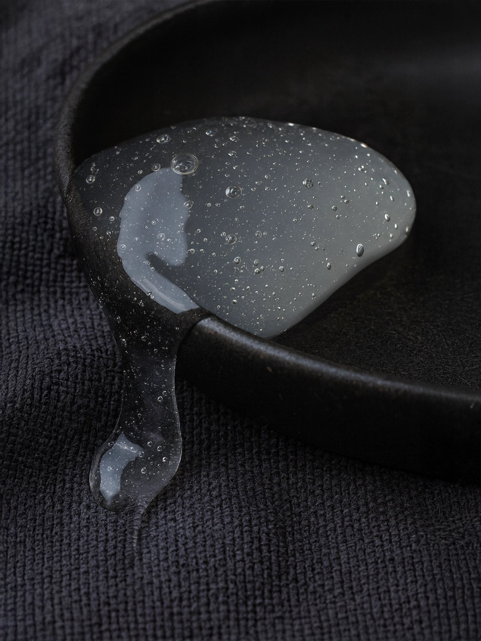 Black and gray guitar pick on a textured black surface