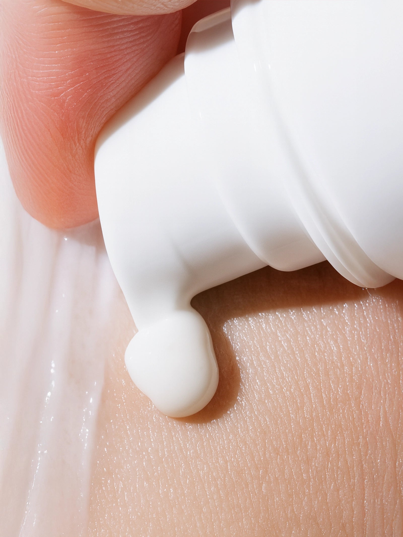 Close-up of a hand applying white cream to skin