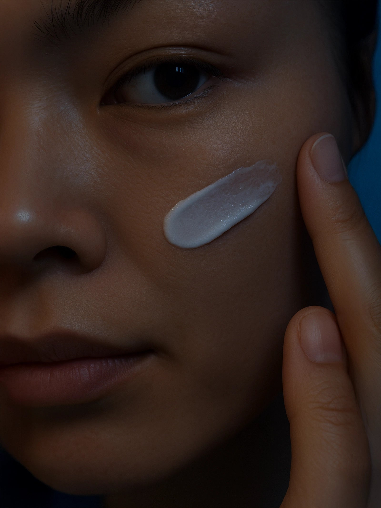 Person applying a skincare product to their face with a finger