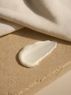 Beige cream smear on a textured beige surface with fabric in the background