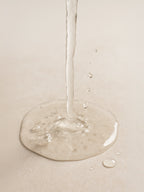 Close-up of a droplet of water on a beige surface Glycolic Acid Liquid Exfoliator