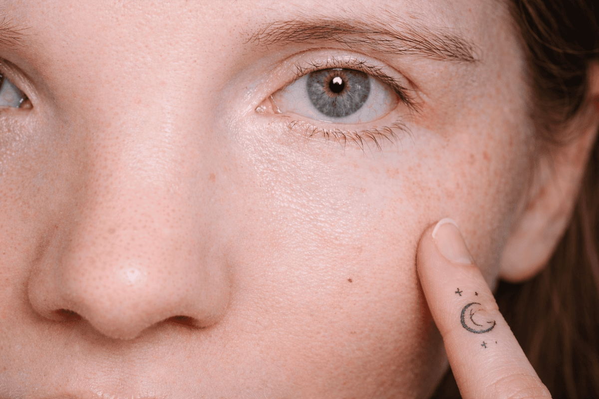 Close-up of a person's eye with a finger pointing to the skin texture.