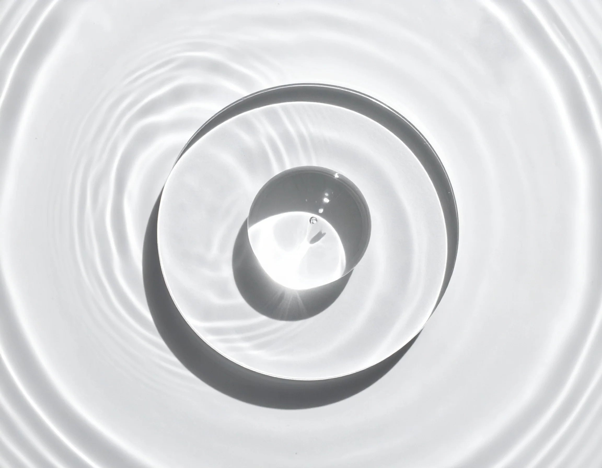 Close-up of water droplets creating concentric circles on a white surface Natural ECOCERT Selfcare Skin Care Hyalyronic Acid Ingredient INCI