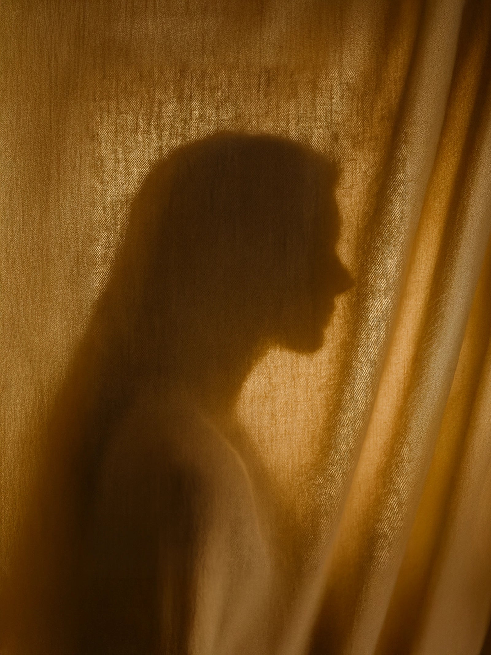 Suvéra Self Care — soft profile silhouette of a woman behind sunlit linen drapery with warm folds and gentle glow.