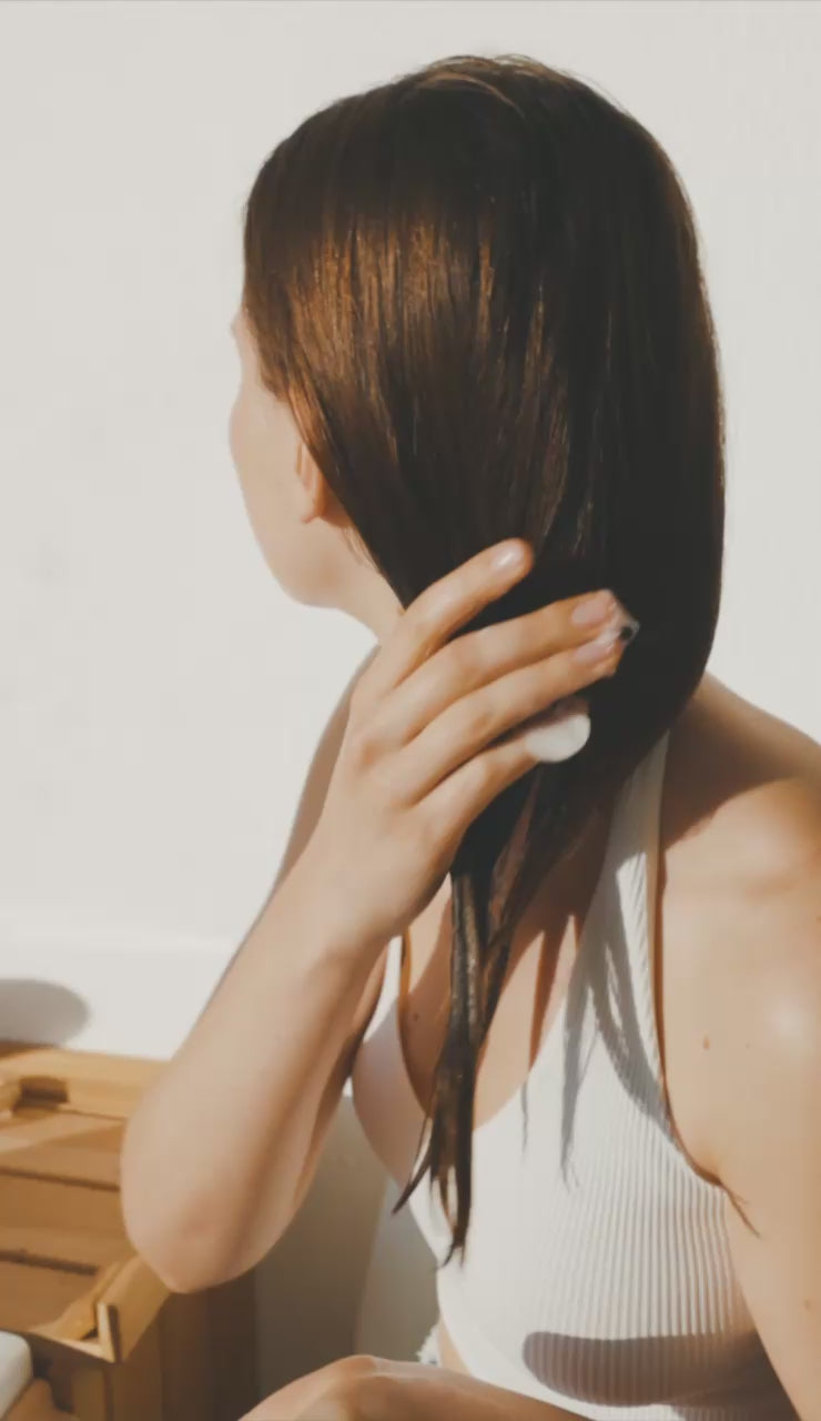 Creamy off-white conditioner smear on translucent glass surface, realistic hand-applied texture, Suvéra hair care for healthy, hydrated shine.