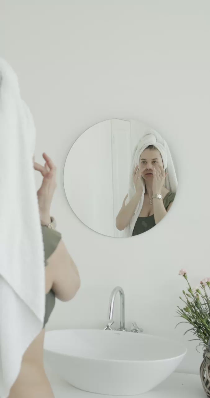 Female skincare model for Suvera applying cream Collagen natural serum to face in bathroom