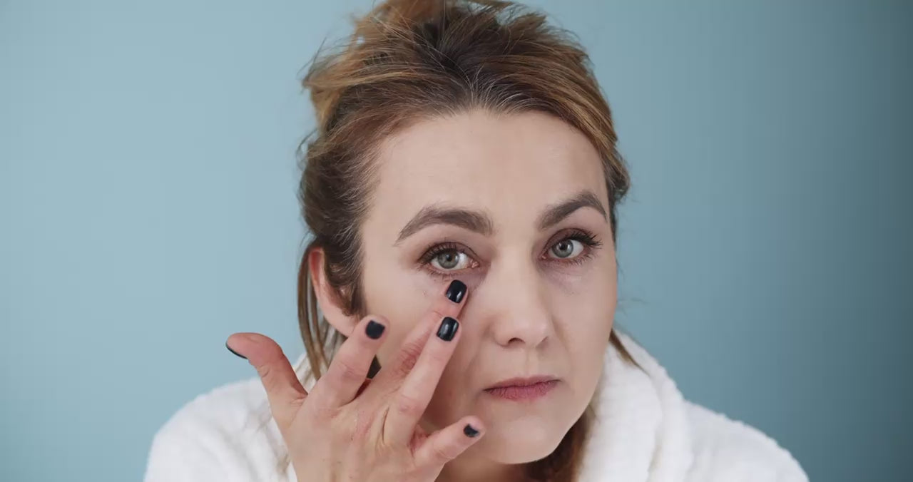 Hand skincare detail—index finger smoothing a thin swipe of lotion on the back of the other hand.
